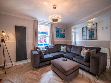 A living room with a large sectional sofa ottoman floor lamp and wall art at Green Retreat in Dartmouth