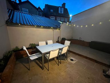 An outdoor patio with a table and six chairs and string lights on the wall at Green Retreat in Dartmouth