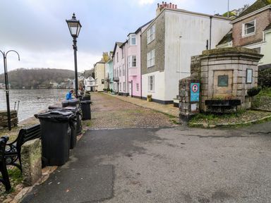 A waterfront street with townhouses a cobblestone walkway and black trash bins along the side at Green Retreat in Dartmouth