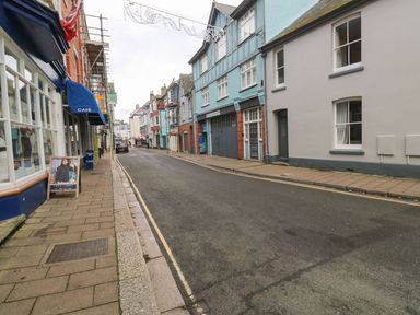 A street with buildings shops and a cafe with a blue awning on a cloudy day