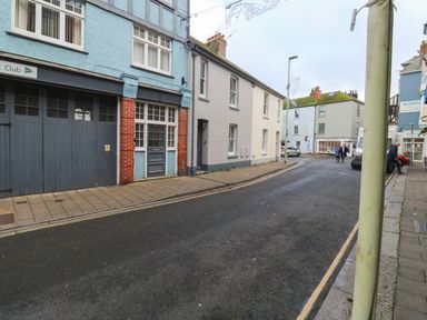 A street with buildings on both sides a few people walking and a van parked at Green Retreat in Dartmouth