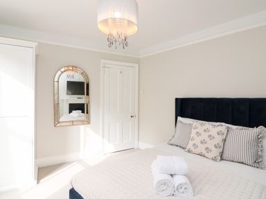 A bedroom with a bed with pillows and towels a chandelier a mirror and a wardrobe at Green Retreat in Dartmouth