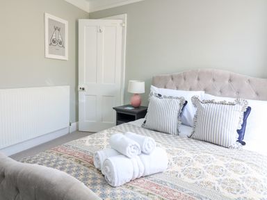 A bedroom with a bed with striped pillows and rolled towels a nightstand with a lamp and an open door at Green Retreat in Dartmouth