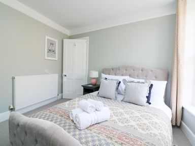 A bedroom with a bed with pillows and folded towels on it a bedside table with a lamp a radiator and a door at Green Retreat in Dartmouth
