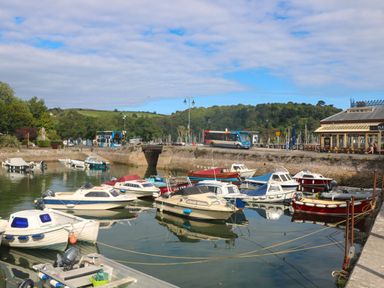 A small harbor with moored boats beside a road with buses and a building at Green Retreat in Dartmouth