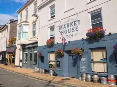 Exterior view of a street with a pub named Market House Inn and neighboring shops in Dartmouth