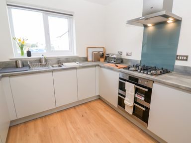 A kitchen with a sink near a window a gas stove oven and countertop appliances at The Bright House in St Eval near St Columb Major