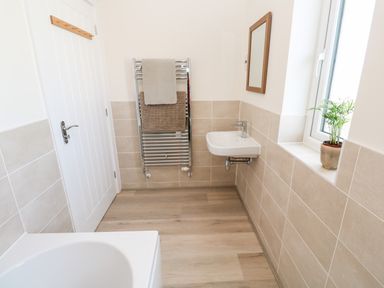 A bathroom with a sink towel rack bathtub window and potted plant at The Bright House in St Eval near St Columb Major