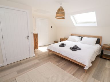 A bedroom with a double bed with white bedding and two rolled towels on the bed two bedside tables and a skylight window at The Bright House in St Eval near St Columb Major
