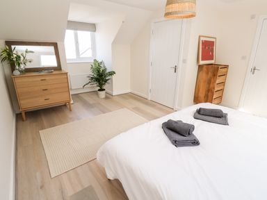 A bedroom with a bed folded towels a dresser a plant and a small chest of drawers at The Bright House in St Eval near St Columb Major