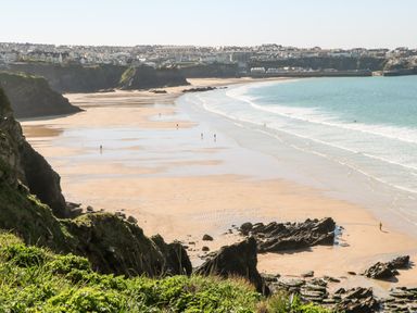 A beach with sand cliffs and houses in the background at The Bright House in St Eval near St Columb Major
