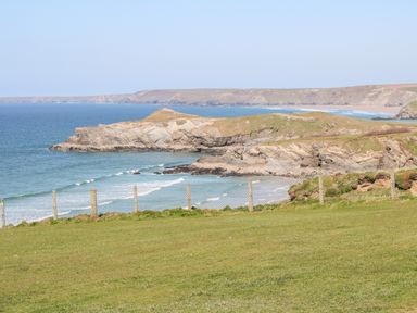 A coastal landscape with grassy cliffs and ocean waves at The Bright House in St Eval near St Columb Major