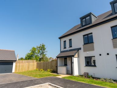 A modern white house with a small front garden and a garage at The Bright House in St Eval near St Columb Major