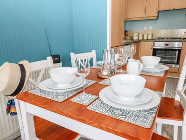 A dining table set with white bowls plates wine glasses and placemats in a kitchen at Lodge Two Country View Park in Graveney