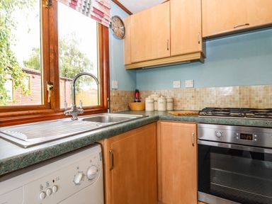 A kitchen with a sink dishwasher oven and canisters by the window at Lodge Two Country View Park in Graveney