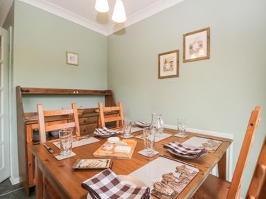 A dining room with a wooden table and chairs set for a meal with cheese plates and glasses at Marsh Garth in Kirkby-In-Furness