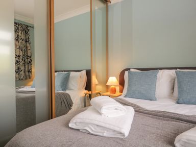 A bedroom with a bed that has blue pillows folded towels and a bedside lamp at Marsh Garth in Kirkby-In-Furness