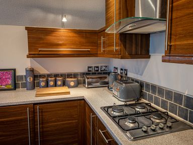 A kitchen corner with gas stove toaster kettle and storage canisters at Lakeland Lodge in Carnforth