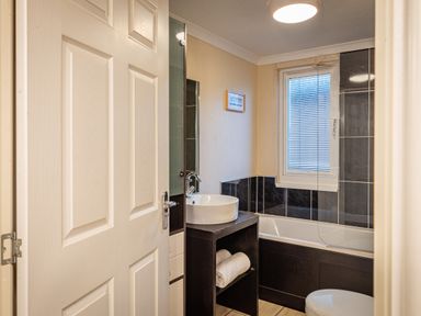 A bathroom with a sink, bathtub, window, and towels at Lakeland Lodge in Carnforth