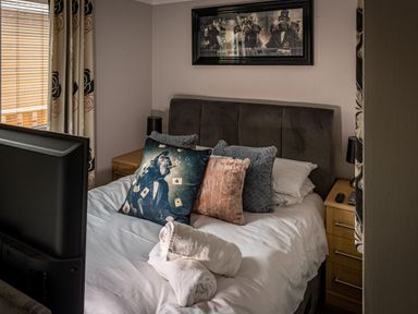 A bedroom with a bed and pillows including one with a chimpanzee wearing a suit at Lakeland Lodge in Carnforth