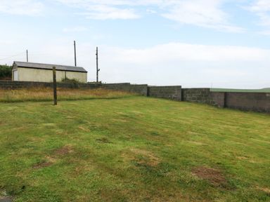 An outdoor area with grass and a building at Faraway in Rhosneigr