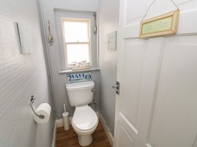 A small bathroom with a toilet a window and wall decorations at Greengate in Tenby