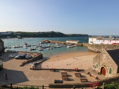 A small harbor with boats docked near a sandy beach and stone buildings at Greengate in Tenby