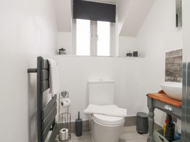 A bathroom with a toilet a towel rack toilet paper holder and a sink on a wooden cabinet at Rosemary Cottage in Briggswath near Sleights