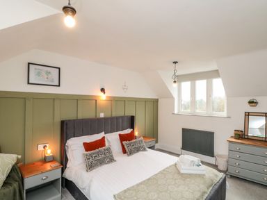 A bedroom with a double bed two bedside tables a chest of drawers and a window at Rosemary Cottage in Briggswath near Sleights
