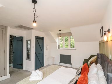 A bedroom with a bed with white and orange pillows a green armchair blue doors and a window at Rosemary Cottage in Briggswath near Sleights