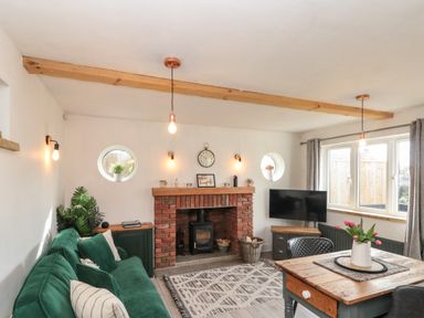 A living room with a green sofa wooden table and a brick fireplace at Rosemary Cottage in Briggswath near Sleights