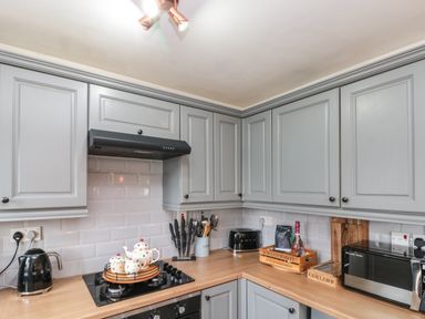 A kitchen corner with grey cabinets wooden countertops stove kettle toaster microwave at Rosemary Cottage in Briggswath near Sleights