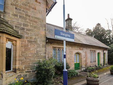 A stone building with green doors and a sign reading Sleights outside at Rosemary Cottage in Briggswath near Sleights