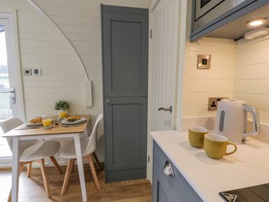 A kitchen area with a small dining table set for two and a countertop with a kettle and two mugs at Y Dderwen in Bontuchel near Ruthin