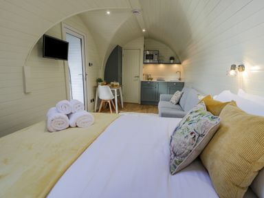 A bedroom with a bed towels sofa kitchenette and dining table at Y Dderwen in Bontuchel near Ruthin