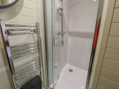 A bathroom with a shower enclosure and a chrome towel radiator at Y Dderwen in Bontuchel near Ruthin