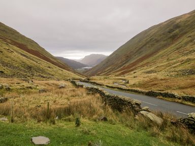 A road running through a valley with stone walls on both sides and hills in the background at 8 Oaks Field in Ambleside