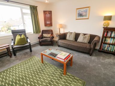 A living room with two armchairs a sofa and a small table with books at 8 Oaks Field Ambleside