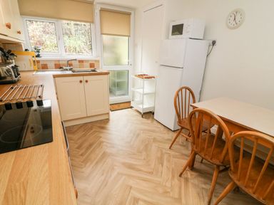 A kitchen with wooden chairs and table a white fridge a microwave and a countertop with a sink at 8 Oaks Field in Ambleside