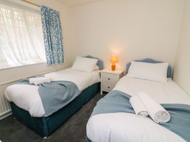 A bedroom with two single beds and a nightstand with a lamp at 8 Oaks Field in Ambleside