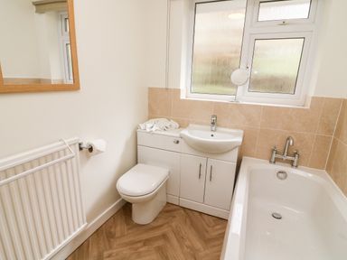 A bathroom with a toilet sink cabinet bathtub radiator and a window at 8 Oaks Field in Ambleside