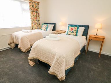 A bedroom with two single beds side by side with beige bedspreads and floral pillows at 8 Oaks Field Ambleside