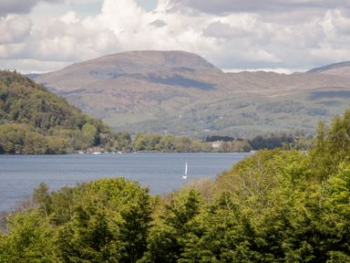 A lake with sailboats surrounded by trees and mountains at Bowness Central in Bowness-On-Windermere