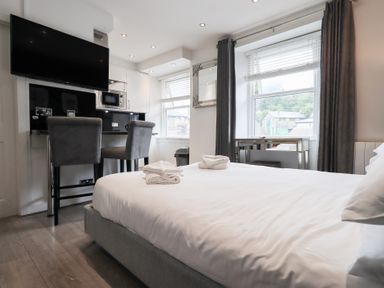 A bedroom with a bed and kitchen area at Bowness Central in Bowness-On-Windermere