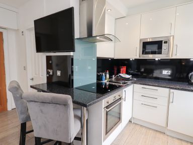 A kitchen with appliances and bar stools at Bowness Central in Bowness-On-Windermere
