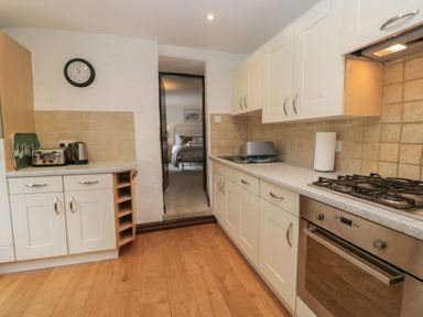 A kitchen featuring cabinets, stove, sink and doorway at Woodloft Cottage Elterwater near Chapel Stile