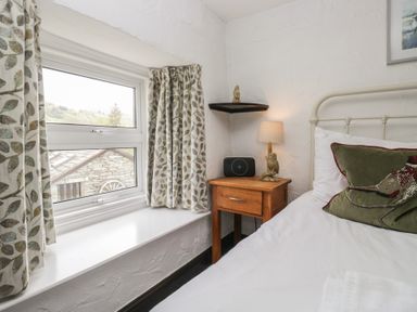A bedroom with a window and bedside table at Woodloft Cottage Elterwater near Chapel Stile