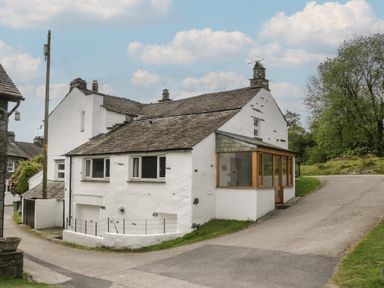 Exterior view of a house with a pathway and trees at Woodloft Cottage Elterwater near Chapel Stile