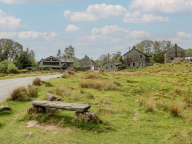 An outdoor area with stone houses and a bench at Woodloft Cottage Elterwater near Chapel Stile