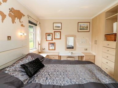 A bedroom with a double bed a window a dressing table and built in wardrobes at 6 Badgers Retreat Tunstall near Richmond